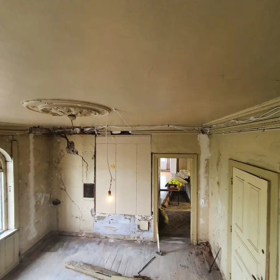 Altbau-Zimmer im Ausgangszustand: Risse im Putz, alte Leitungen, abgenutzter Boden